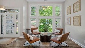 Una habitación amplia con un gran ventanal, una mesa redonda de madera y sillones de cuero.