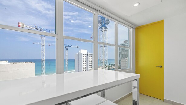 A room with a large window overlooking a construction site and the sea. - Yellow Luxury PH | Steps from the beach in Condado (San Juan)