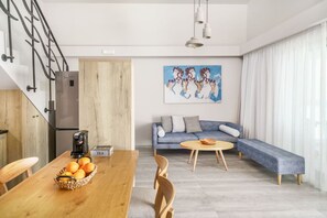 A modern living space with a kitchen, dining area, and a sofa.