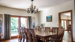 Ein Esszimmer mit einem großen Holztisch und Stühlen, einer Kristallleuchter und einem Gemälde an der Wand.