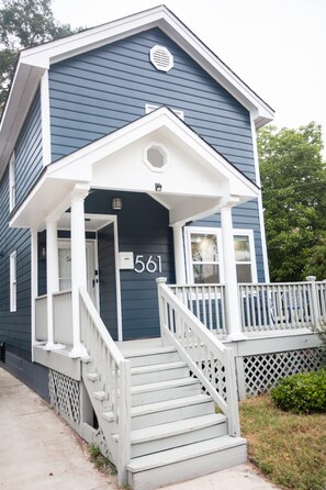 A two-story house with a porch, a set of stairs, and a mailbox.