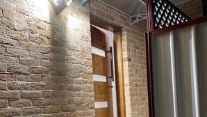 A brick exterior wall with a wooden door and a metal gate.