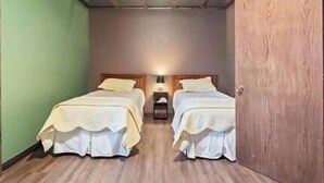 Une chambre avec deux lits, une table de chevet et une armoire en bois.