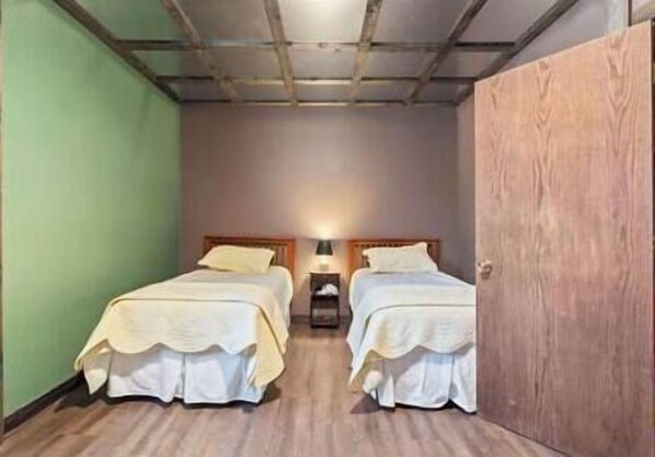 Ein Zimmer mit zwei Betten, einem Nachttisch und einem Holzschrank.
