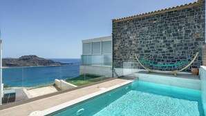 Ein Pool mit freiem Blick auf das Meer und einer Steinmauer.