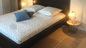 Une chambre à coucher moderne avec un grand lit, deux lampes de chevet et une table de nuit ronde.