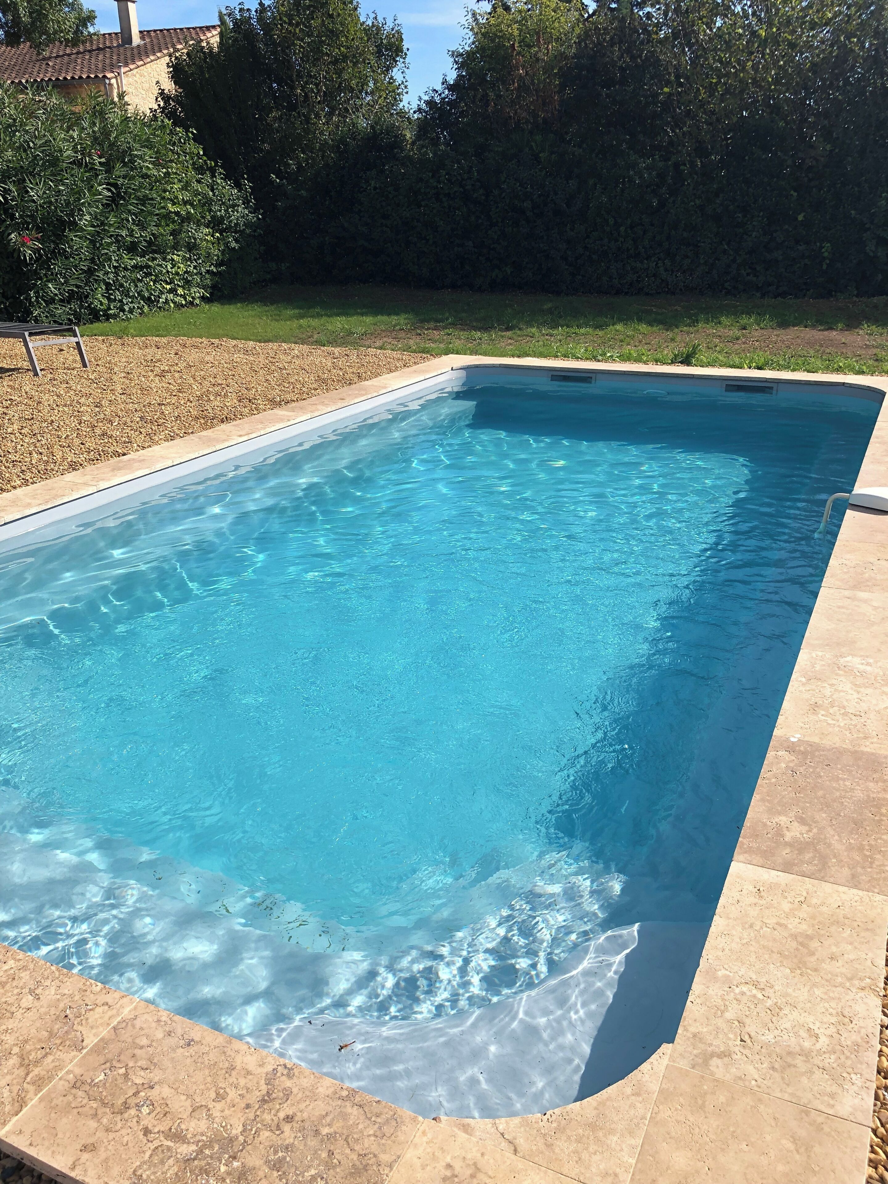 A rectangular swimming pool with clear blue water, surrounded by a tiled deck.