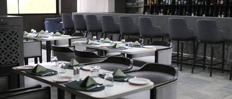 Un restaurante con varias mesas y sillas, dispuestas cuidadosamente con platos, vasos y servilletas.