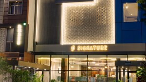 A modern hotel with a prominent 'Signature' sign, large windows, and a well-lit entrance. - Signature Hotel (Ajmer)
