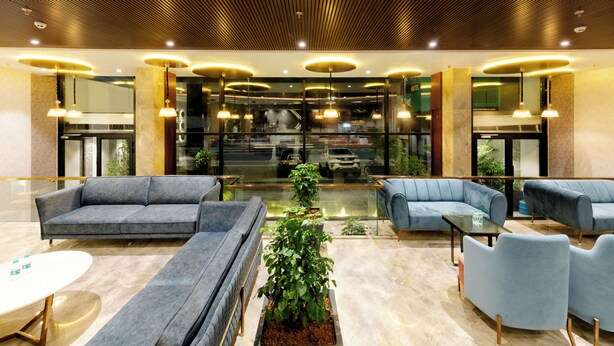 A modern lobby with sofas, a coffee table, and a potted plant. - Signature Hotel (Ajmer)