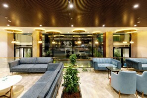 Un hall d’entrée moderne avec des canapés, une table basse et une plante en pot.