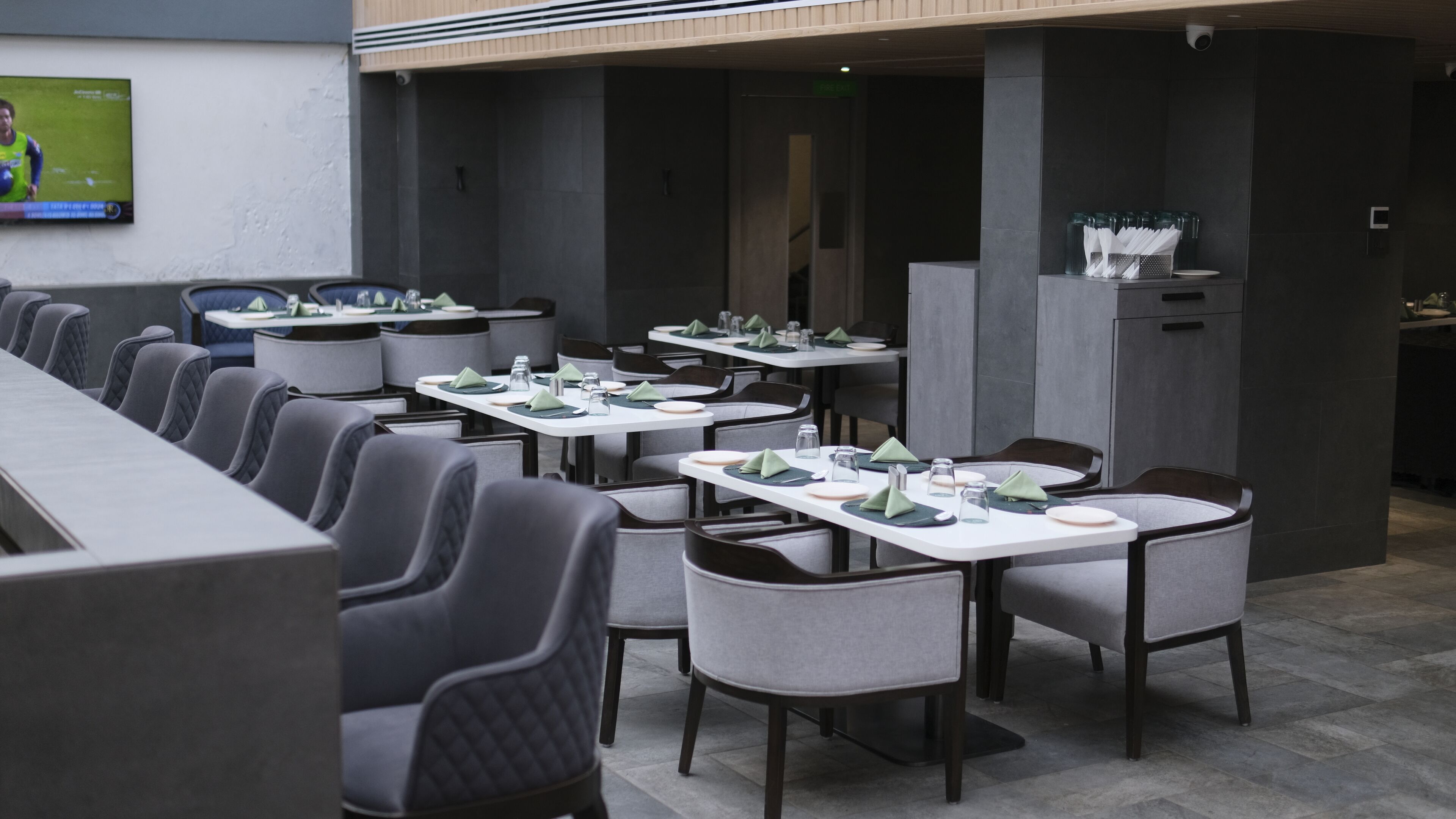 Un restaurant doté de plusieurs tables et chaises, d’un écran de télévision et d’un comptoir.