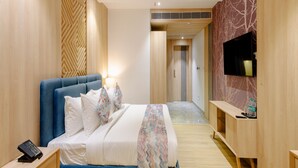 A modern bedroom with a large bed, a TV mounted on the wall, and a wooden floor. - Signature Hotel (Ajmer)