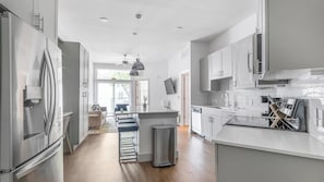 Una cocina moderna con electrodomésticos de acero inoxidable, una isla central y un comedor con sofá y mesa.