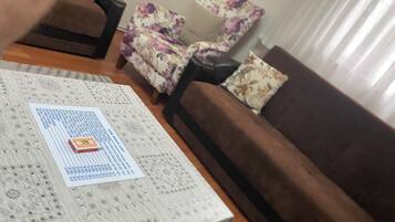 A living room with a patterned coffee table, a brown sofa, and a floral armchair.