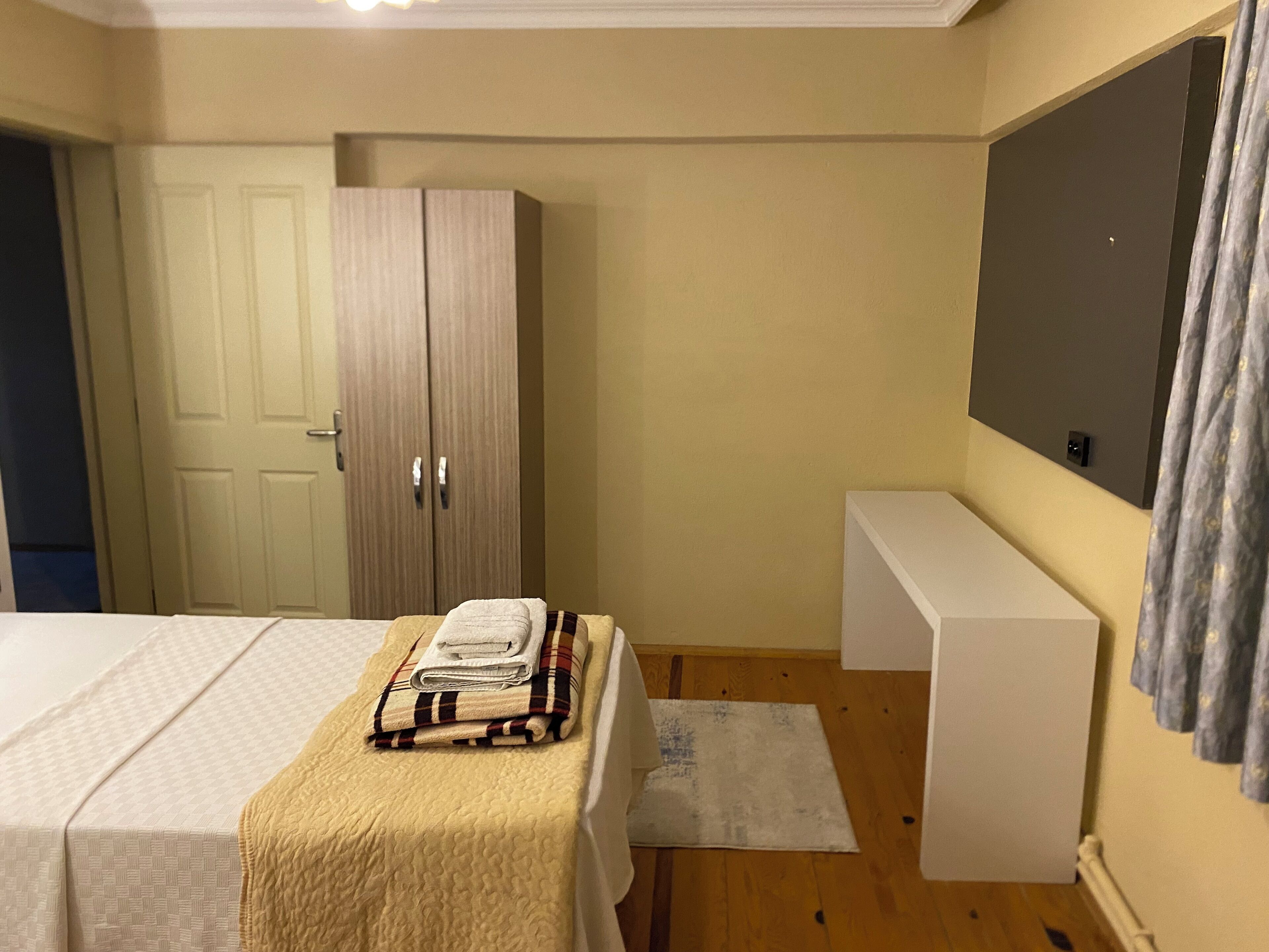 Un dormitorio con cama, armario, banca y televisor de pared.