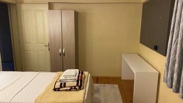 Un dormitorio con cama, armario, banca y televisor de pared.