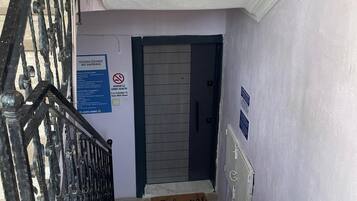 A staircase with a metal railing, a 'Welcome' mat, a 'No Smoking' sign, and a door with a 'Kaygan Zemin' sign.