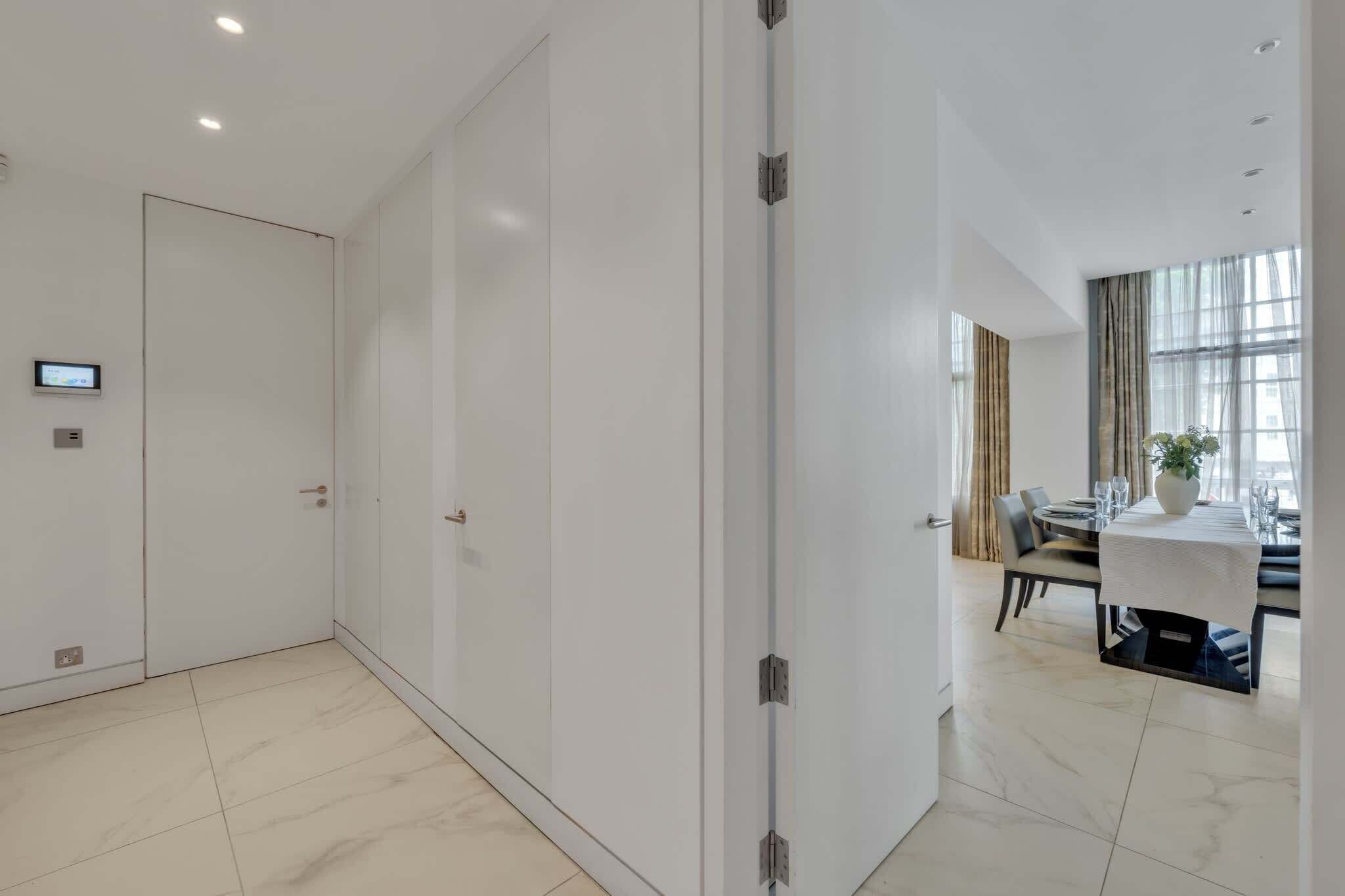 Een moderne hotelkamer met een grote schuifdeur, een zithoek met een tafel en stoelen, en een potplant.
