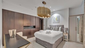 Ein modernes Schlafzimmer mit einem großen Bett, einem Esstisch, einem Fernseher und einem Kleiderschrank.