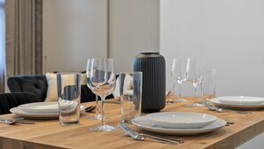 A dining table set with plates, glasses, and cutlery, with a vase and a chair in the background. - Stylish Apartment with AC in Baker St (Greater London)