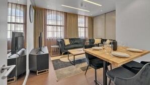 A modern living room with a sofa, coffee table, and dining table set for six. - Stylish Apartment with AC in Baker St (Greater London)