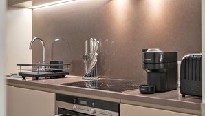 A modern kitchen with a built-in dishwasher, a coffee machine, and a kettle. - Stylish Apartment with AC in Baker St (Greater London)