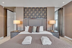 A hotel room with a large bed, two bedside tables, a headboard with a floral pattern, and a view of the outside through a window. - 2B Flat with lift and AC in Baker St (Greater London)