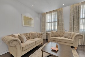A modern living room with two beige sofas, a coffee table, and patterned curtains. - Beautiful apartment with lift in Baker St (Greater London)