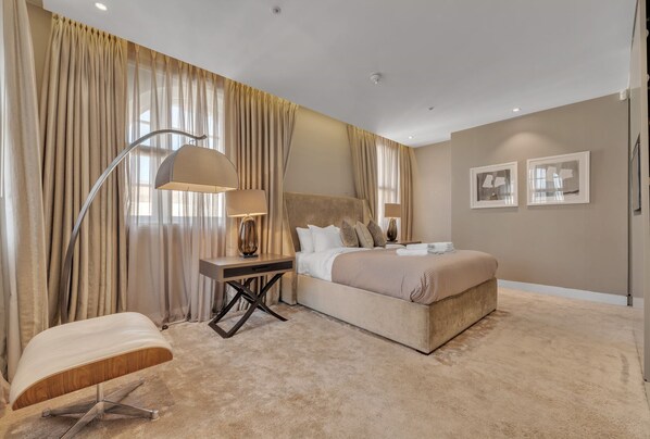 A modern bedroom with a large bed, a bedside table with a lamp, and a chair. - Beautiful apartment with lift in Baker St (Greater London)
