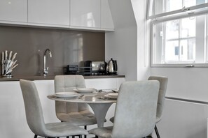 A modern kitchen with a dining area, featuring a round table, four chairs, and a window.