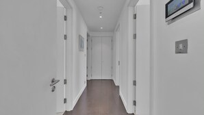 Un pasillo moderno con paredes blancas, piso de baldosas y una pantalla digital montada en la pared.