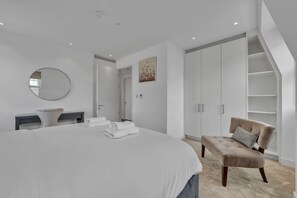 A bedroom with a large bed, a bedside table, a chair, a wardrobe, and a mirror. - Modern loft with AC and lift in Baker St (Greater London)