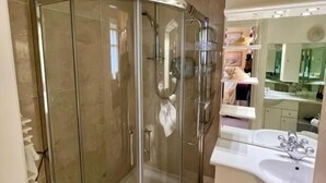 Un baño moderno con ducha de vidrio, tocador con espejo y lavamanos.