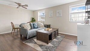 Een moderne woonkamer met een bank, salontafel en een plafondventilator.