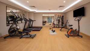 Une salle de sport moderne équipée de tapis de course, de vélos elliptiques et de poids libres.