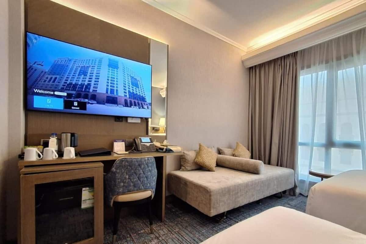 Ein Hotelzimmer mit Fernseher, Schreibtisch, Stuhl, Sofa und einem Bett.