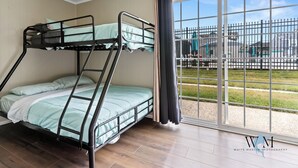 A bunk bed room with a large window and a view of a fenced area outside. - Charming 2nd Floor Bayside Condo, Steps to Pool & Beach! (Ocean City)