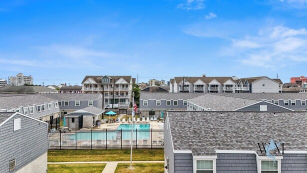 A residential area with multiple two-story houses, a swimming pool, and a fenced patio area. - Charming 2nd Floor Bayside Condo, Steps to Pool & Beach! (Ocean City)
