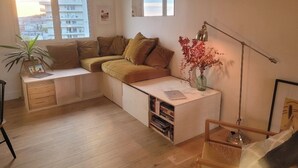 A cozy living room with a sofa, a desk, a lamp, and a view of the city. - Buttes Chaumont top floor loft: unobstructed view of Paris! (Paris)