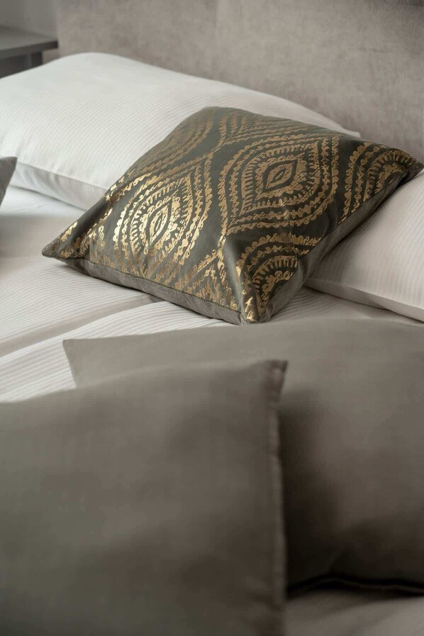 A bed with a patterned pillow and a plain pillow.