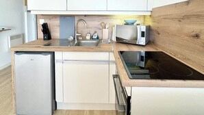 Una cucina compatta con mobili bianchi, lavastoviglie integrata, lavello e tostapane.