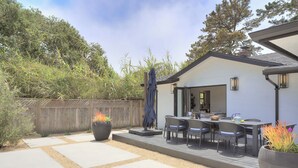 A patio with a dining table and chairs, a barbecue grill, and a large planter with plants. - 3944 Seaside Bash - Central Carmel Location (Carmel)