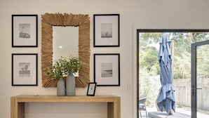 A modern living room with a wooden console table, a blue ottoman, a decorative mirror, and framed pictures on the wall. - 3944 Seaside Bash - Central Carmel Location (Carmel)