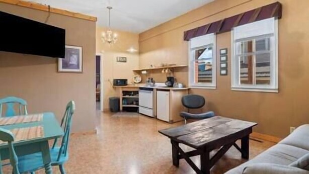 Un espacio habitable compacto con kitchenette, un comedor con mesa y sillas, y un sofá.