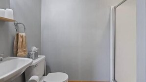 Un baño pequeño con inodoro, lavamanos y toallero.
