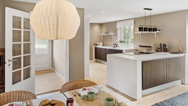 A modern kitchen with a central island, white cabinetry, and a hanging pendant light.