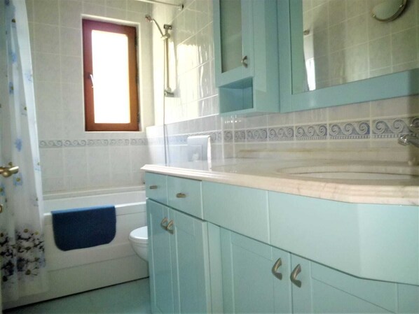 A bathroom with a bathtub, toilet, and sink.