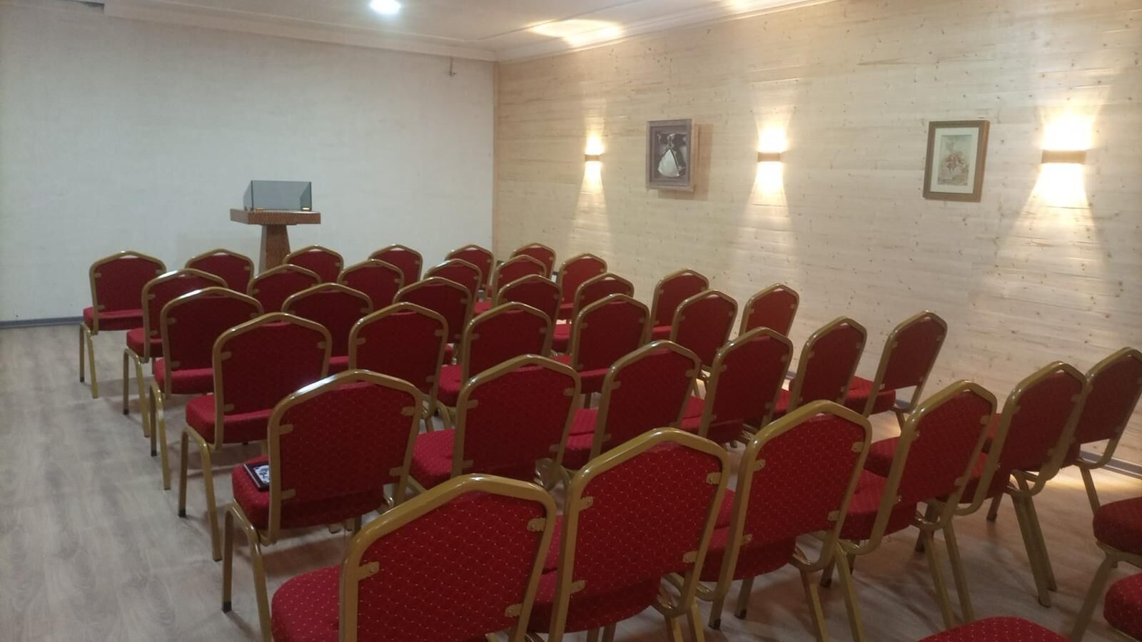 A room with rows of red chairs and a podium.