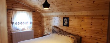 Una habitación con paneles de madera, una cama, un radiador, una ventana con cortinas y un cuadro enmarcado en la pared.